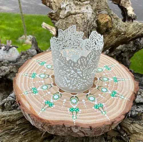 Decorative candle holder on wooden slice outdoors.