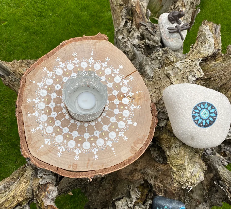 Kerze auf Holzscheibe mit Mandala-Design.