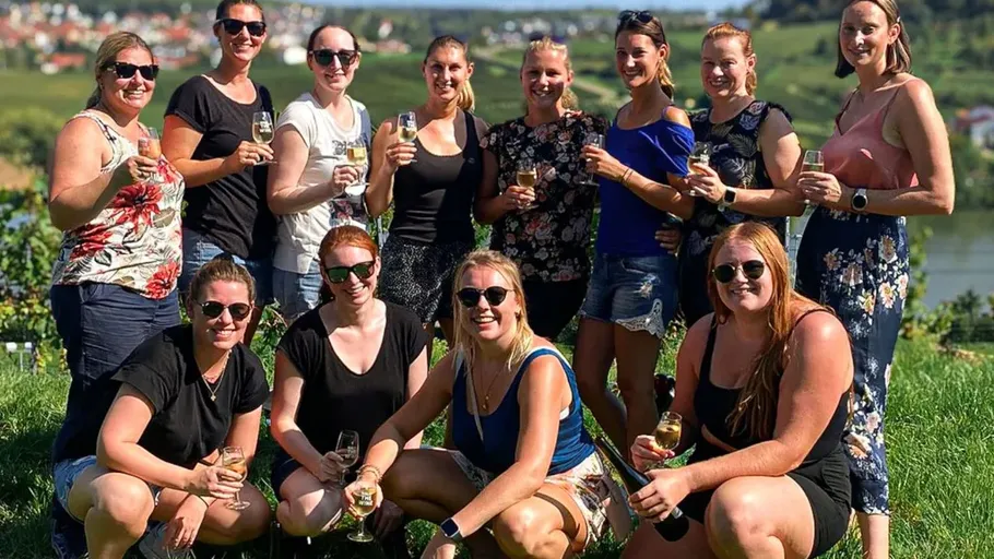 Gruppe von Frauen posiert draußen mit Getränken.