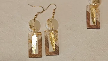 Goldene Federohrringe auf weißem Hintergrund.