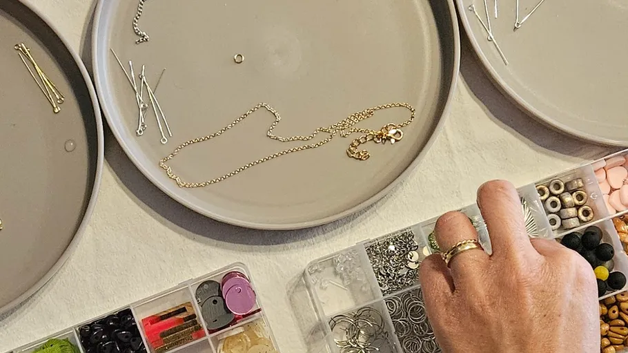 Hand organizing jewelry on plates and boxes.