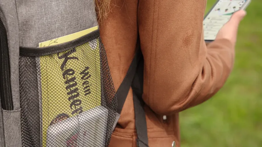Backpack with magazine, person using phone.