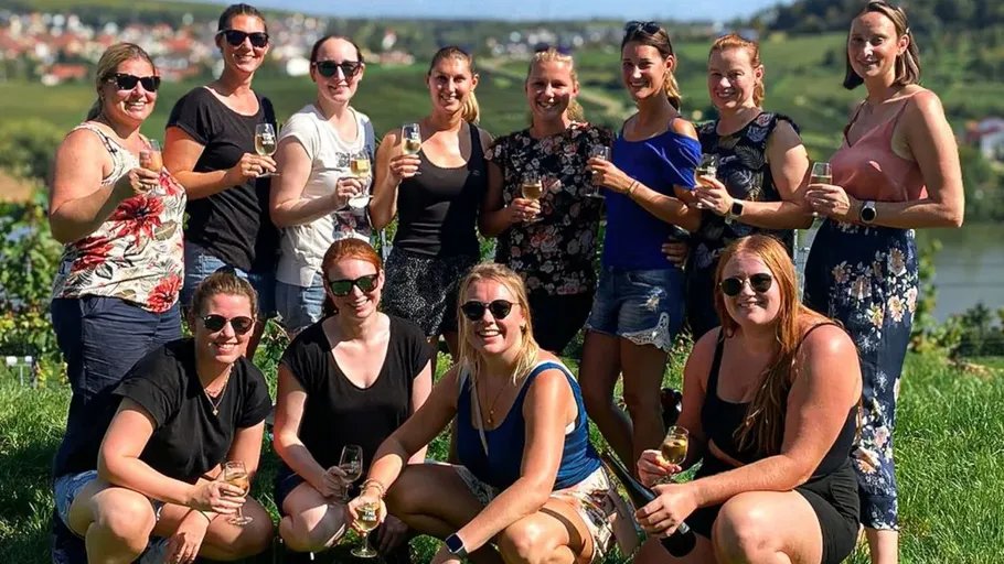 Group of women holding wine in vineyard.