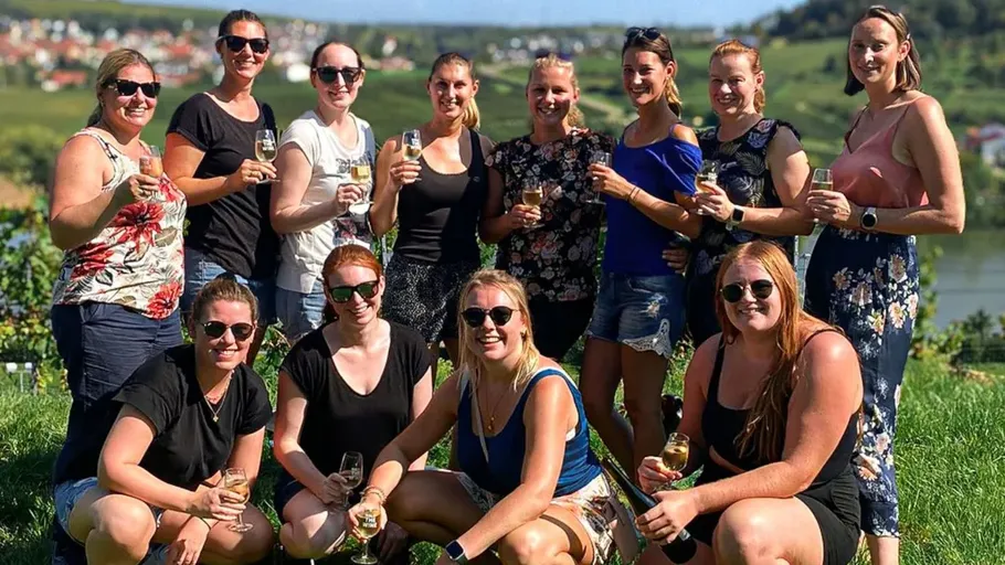 Group of women holding glasses in vineyard.