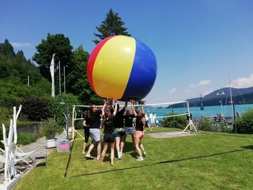 Große, bunte Ball wird von Personen in der Natur gehalten.