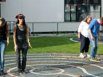 Four people are playing an orientation game in a garden.