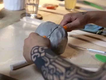 A person forms gray dough on a table.