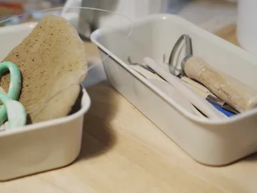Schalen mit Werkzeugen und Schwämmen auf einem Tisch.