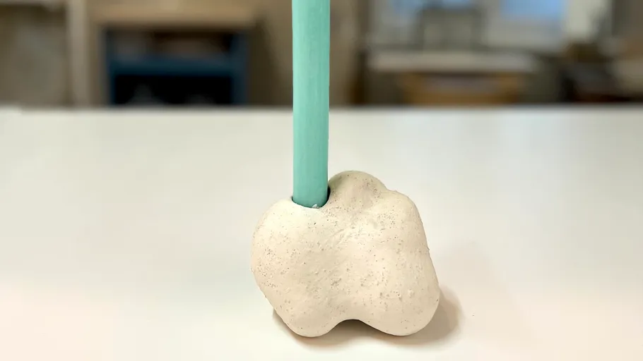 Kerze in einzigartigem Halter auf Tisch.