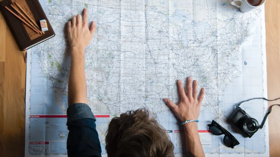 Person studying map on wooden table.