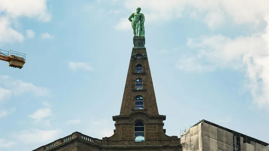 Statue auf einem hohen Turmspitz.