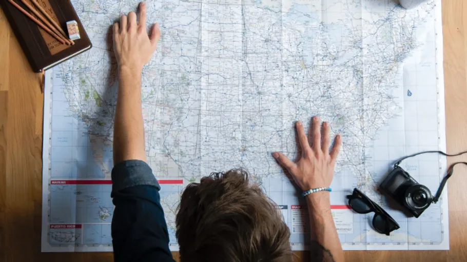 Person studiert Karte auf Holztisch.