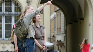 Person pointing while another smiles, urban setting.