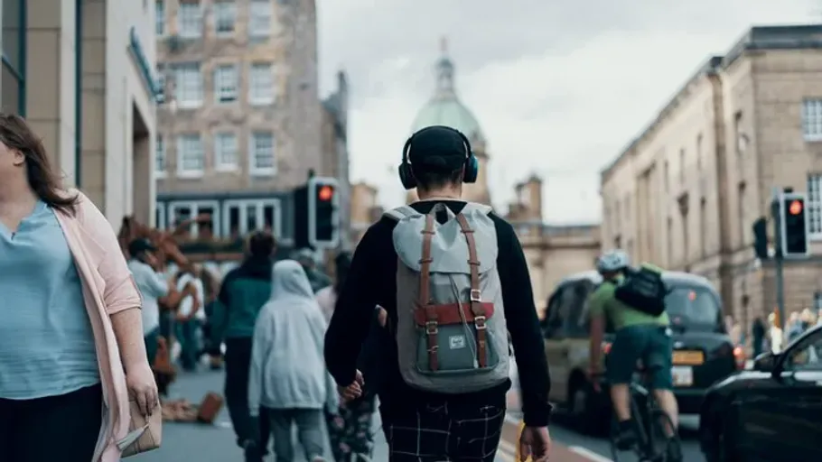 Person wearing headphones walking in city street.