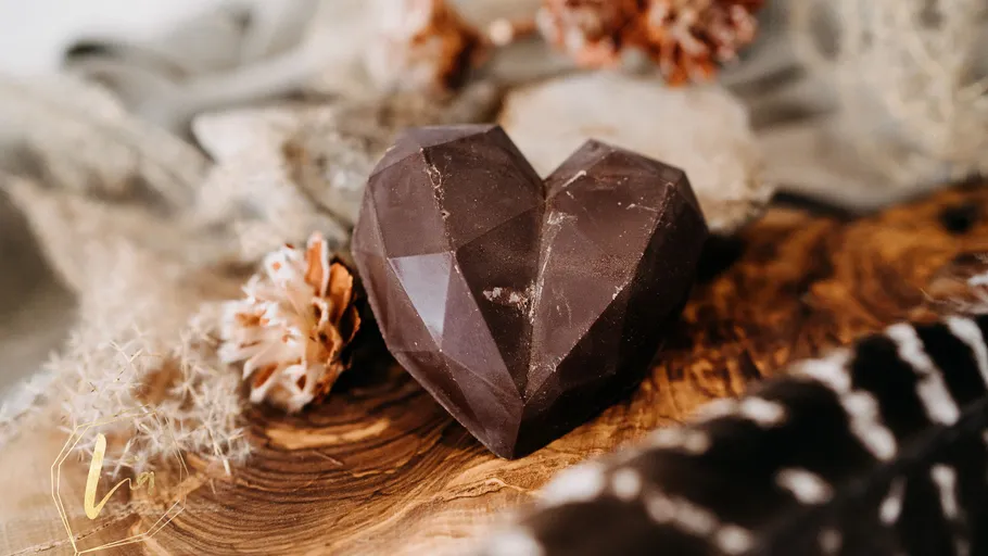 Faceted chocolate heart on wooden surface.