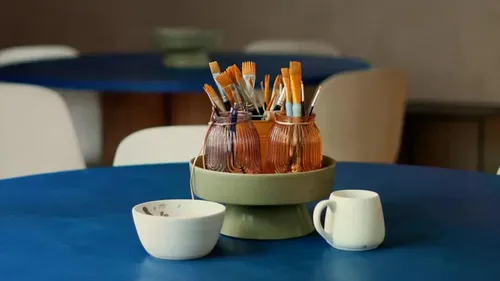 Paintbrushes in jars on a table.