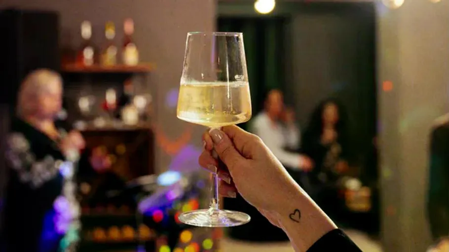 Hand hält Weinglas in Partykulisse.