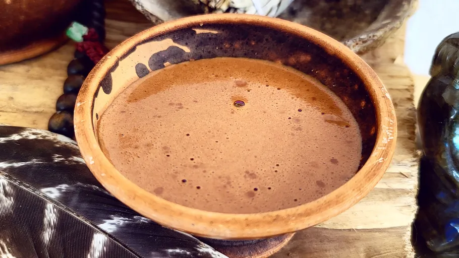 Brown liquid in a wooden bowl, rustic setting.