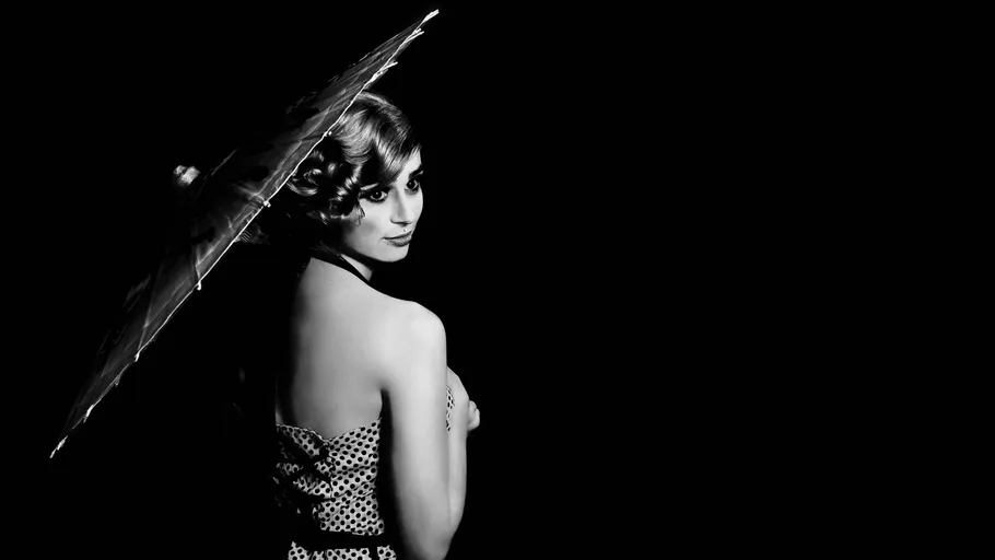 Woman with umbrella in black background.