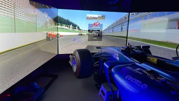 Racing simulator cockpit with three-screen setup.