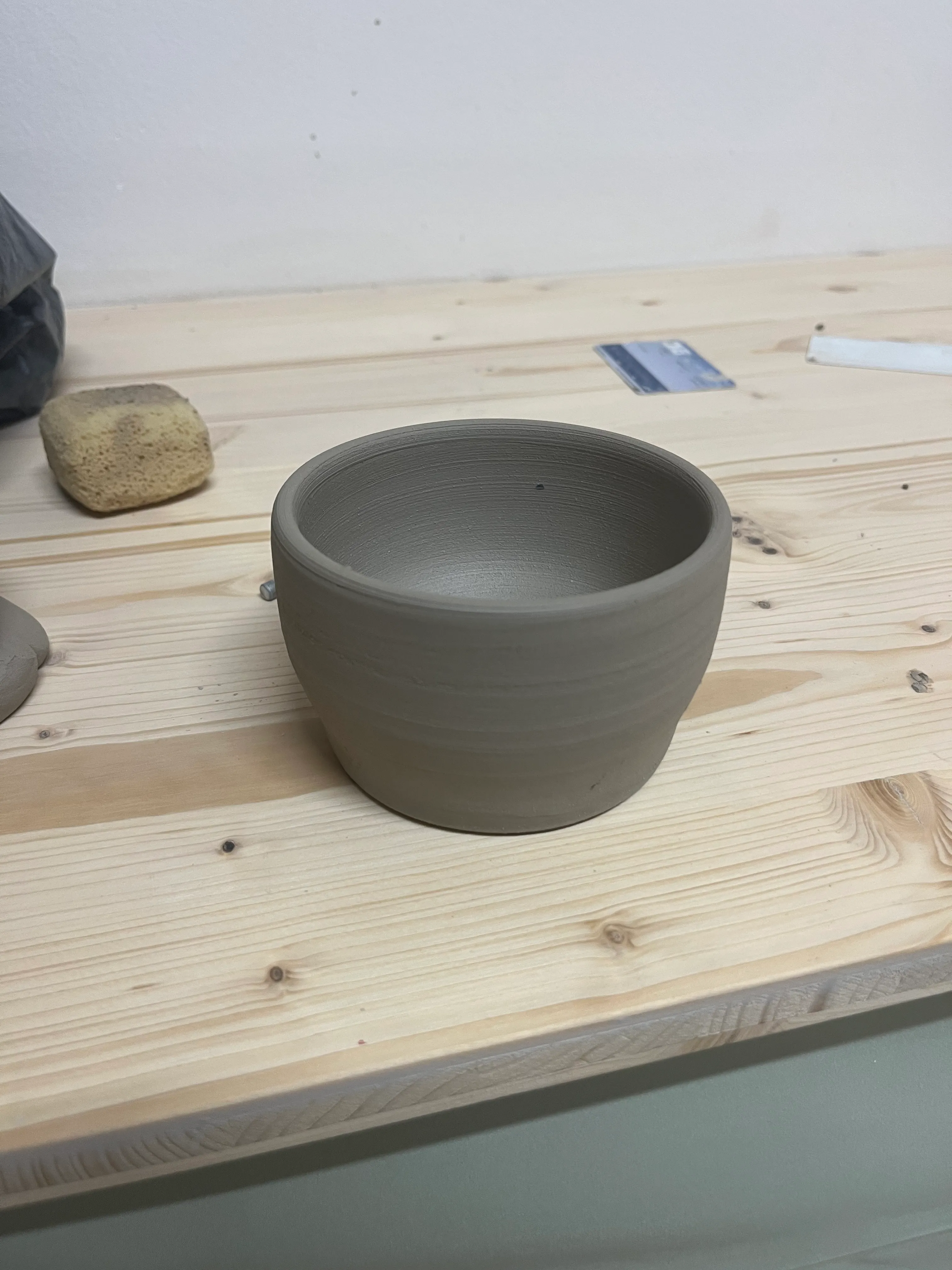 Tonschüssel steht auf einem Holztisch.