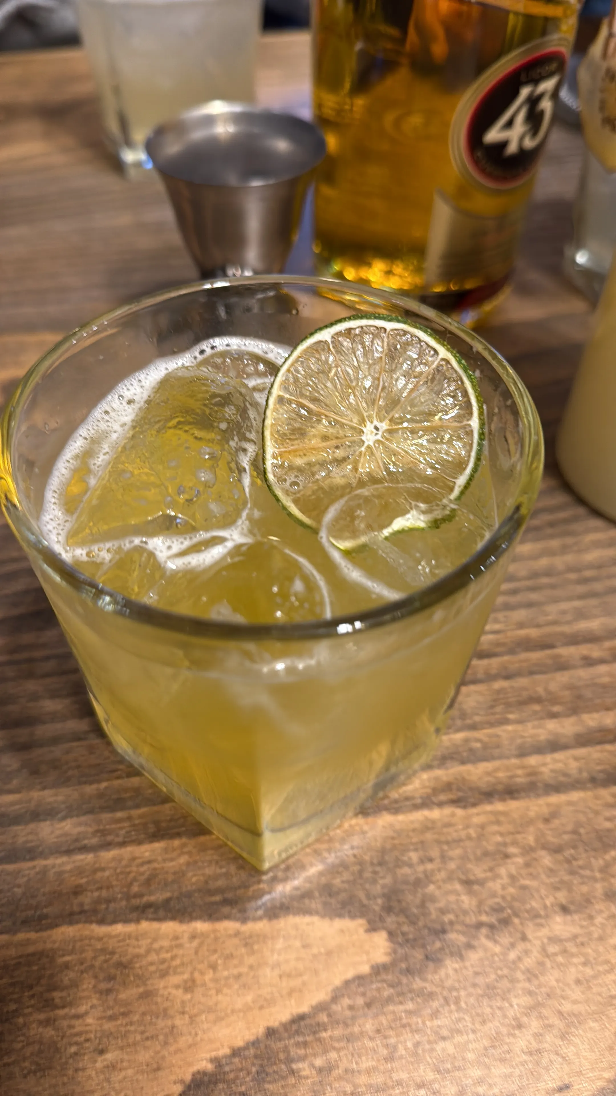 Glas mit Cocktail und Limettenscheibe auf Holztisch.