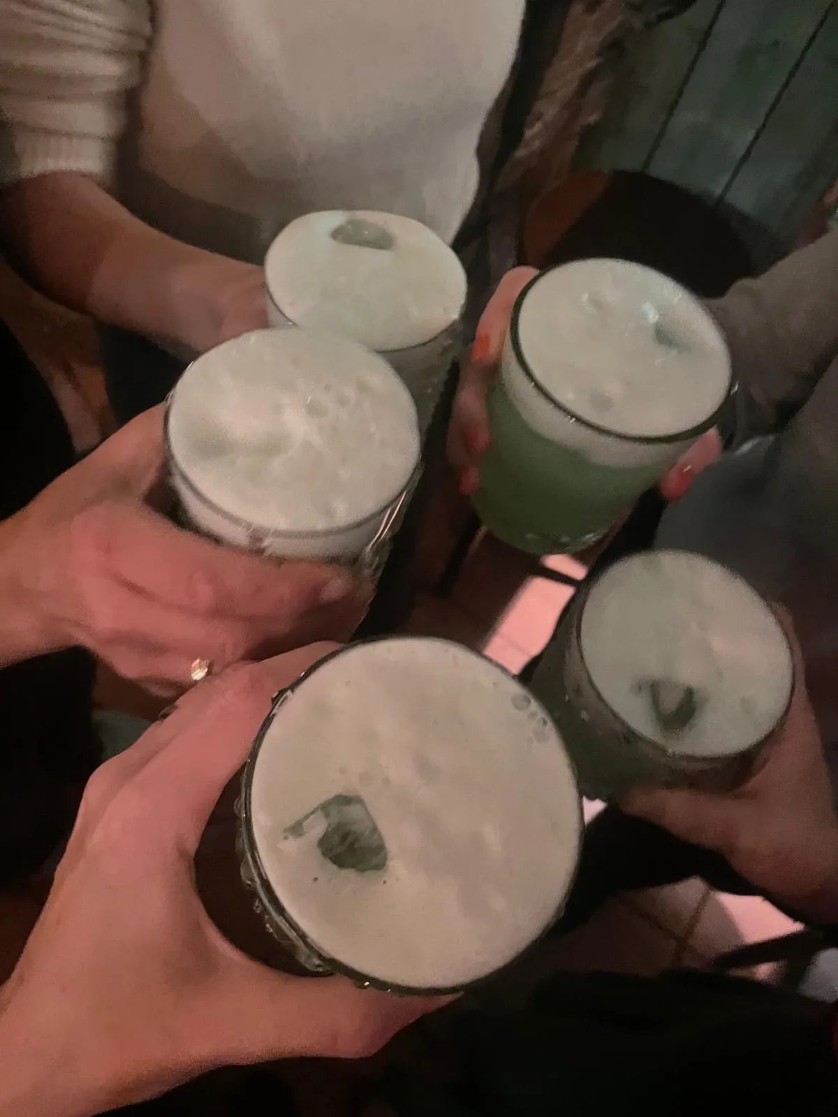 Hände stoßen Bierkrüge in einer Bar an.