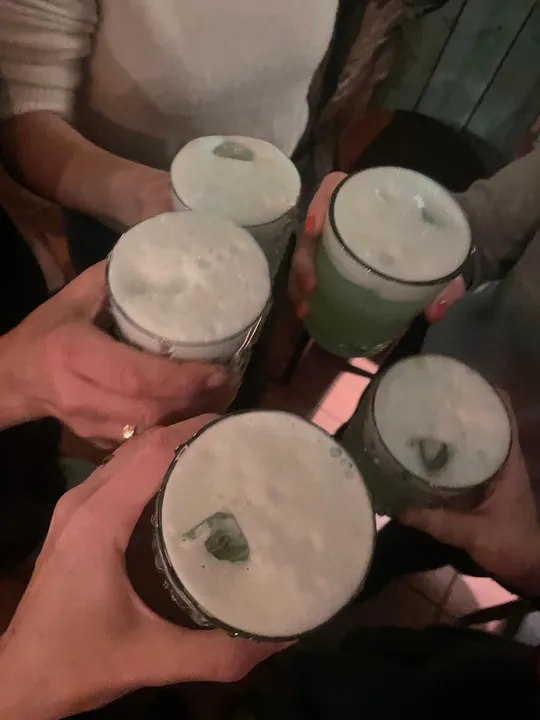 Hands clinking beer mugs in a bar.