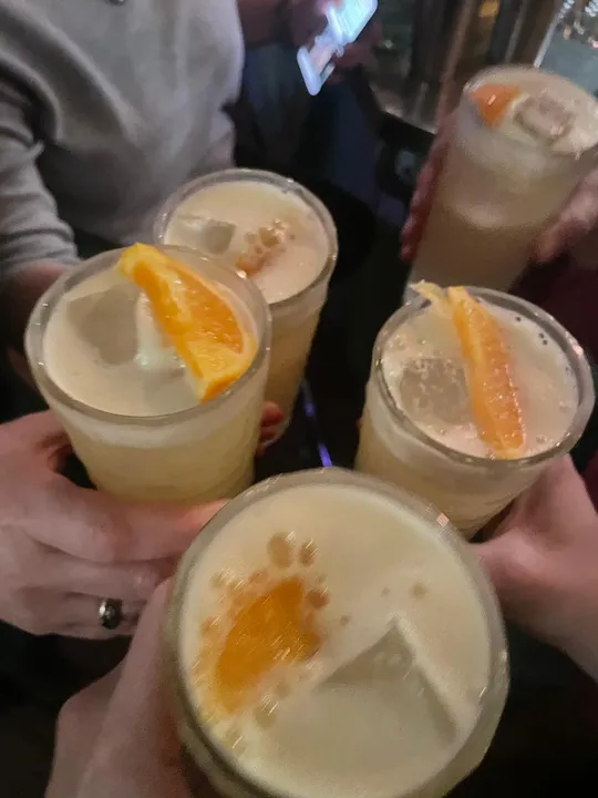 Four drinks with orange slices in a toast.
