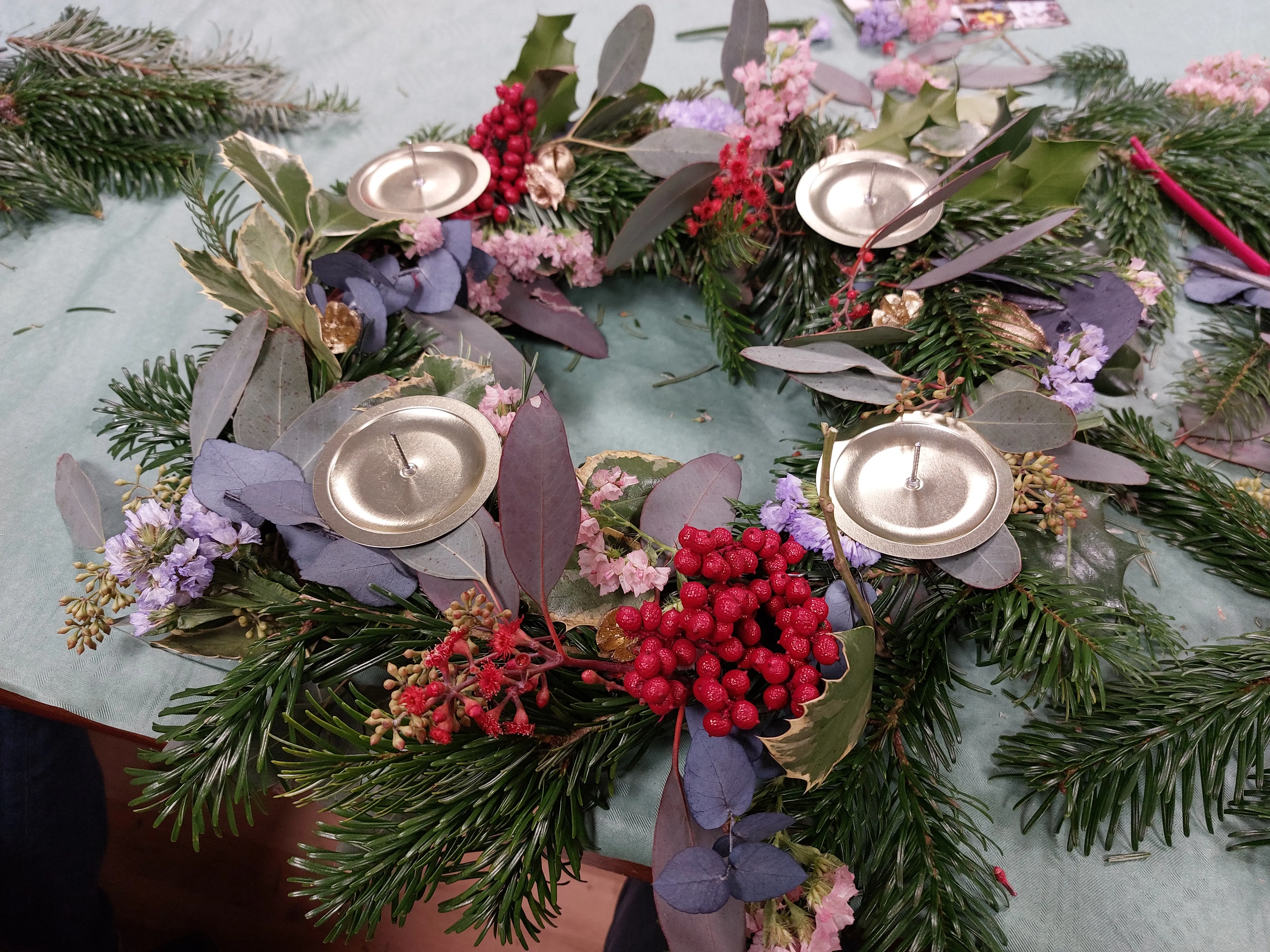 Decorated wreath with candles on table.