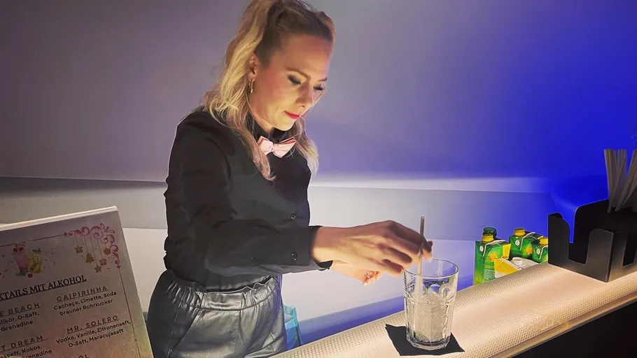 Bartender mixing drink behind counter.