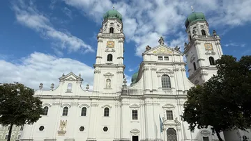 White cathedral with two green domes, clear sky.
