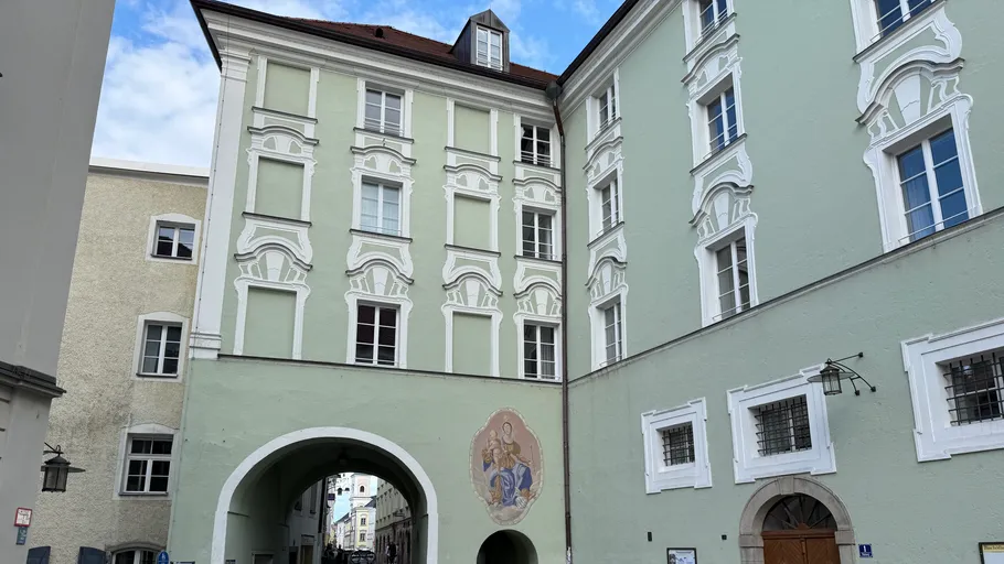 Green historical building with arched passage.