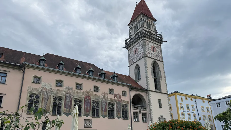 Historischer Turm mit Wandbildern und bewölkter Himmel.