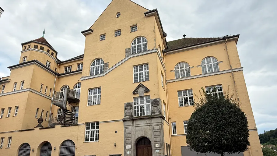 Yellow building with arched windows under cloudy sky.