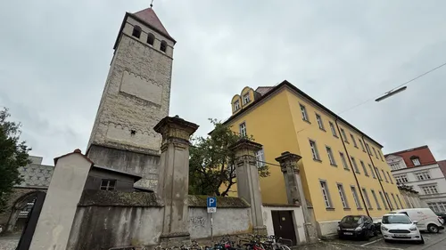 Turm und gelbes Gebäude in städtischer Umgebung.