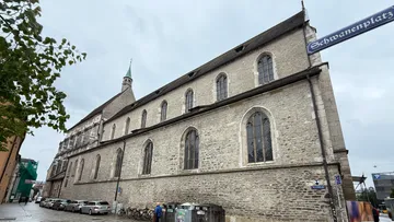 Steinkirchengebäude mit Bogenfenstern, wolkiger Himmel.