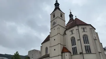 Kirche mit Uhrturm, bewölkter Himmel.