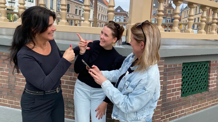 Three women smiling and talking outside.