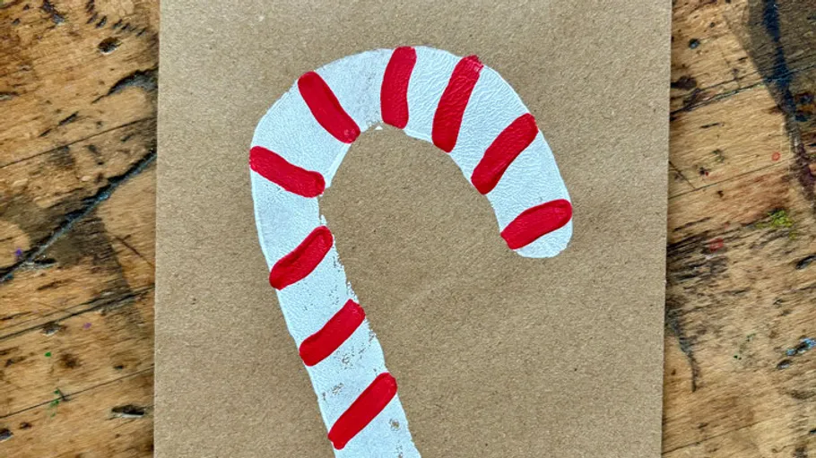 Gemalter Zuckerstab auf braunem Papier.