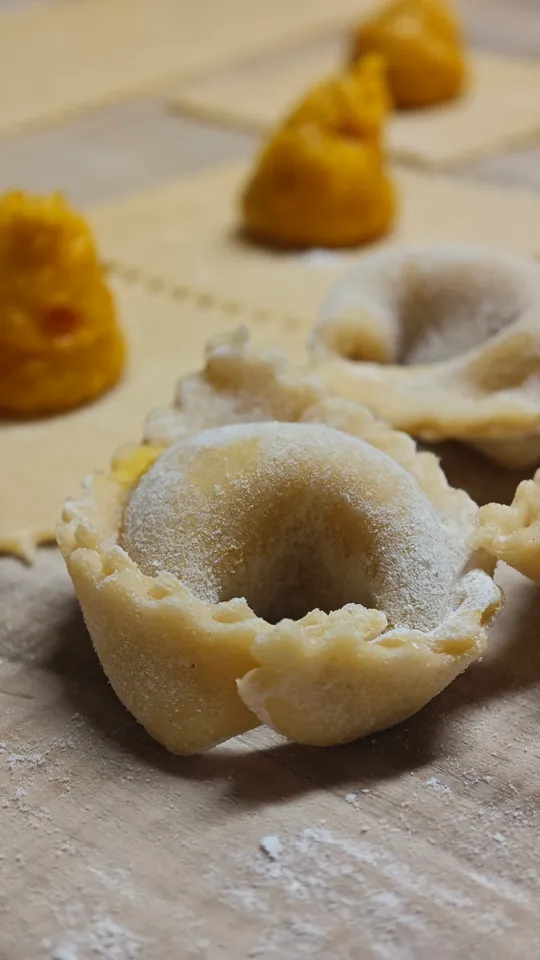 Frische Tortellini auf einer Holzoberfläche vorbereitet.
