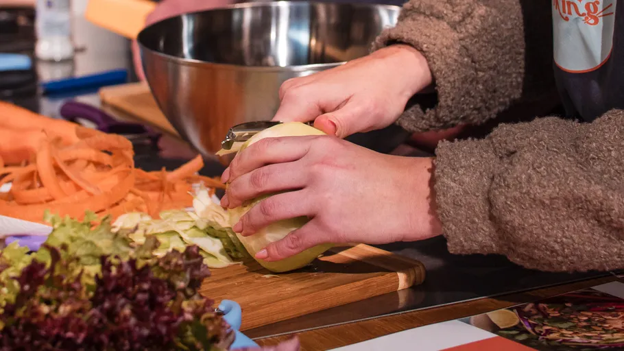 Person peeling vegetable on cutting board.