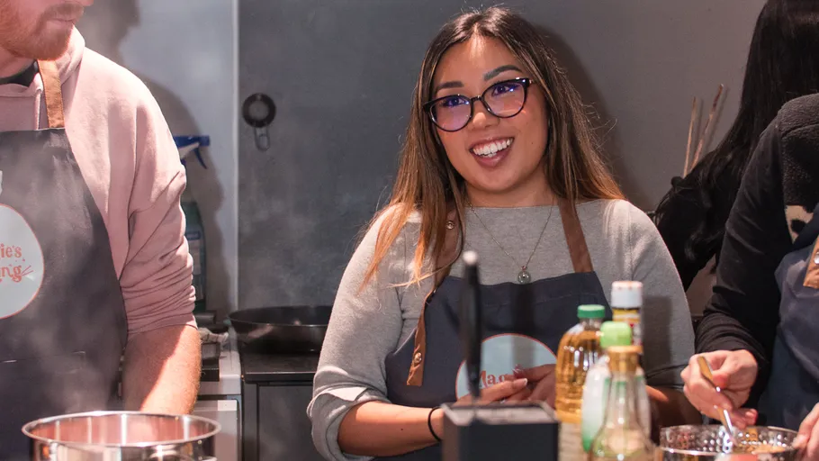 Woman smiling in kitchen with cooking utensils.