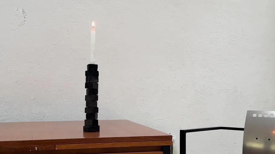 Candle burning on stacked magnets on table.