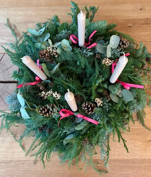 Adventskranz mit Kerzen auf Holztisch.