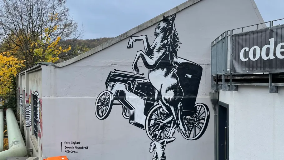 Horse mural on wall with cart, urban setting.