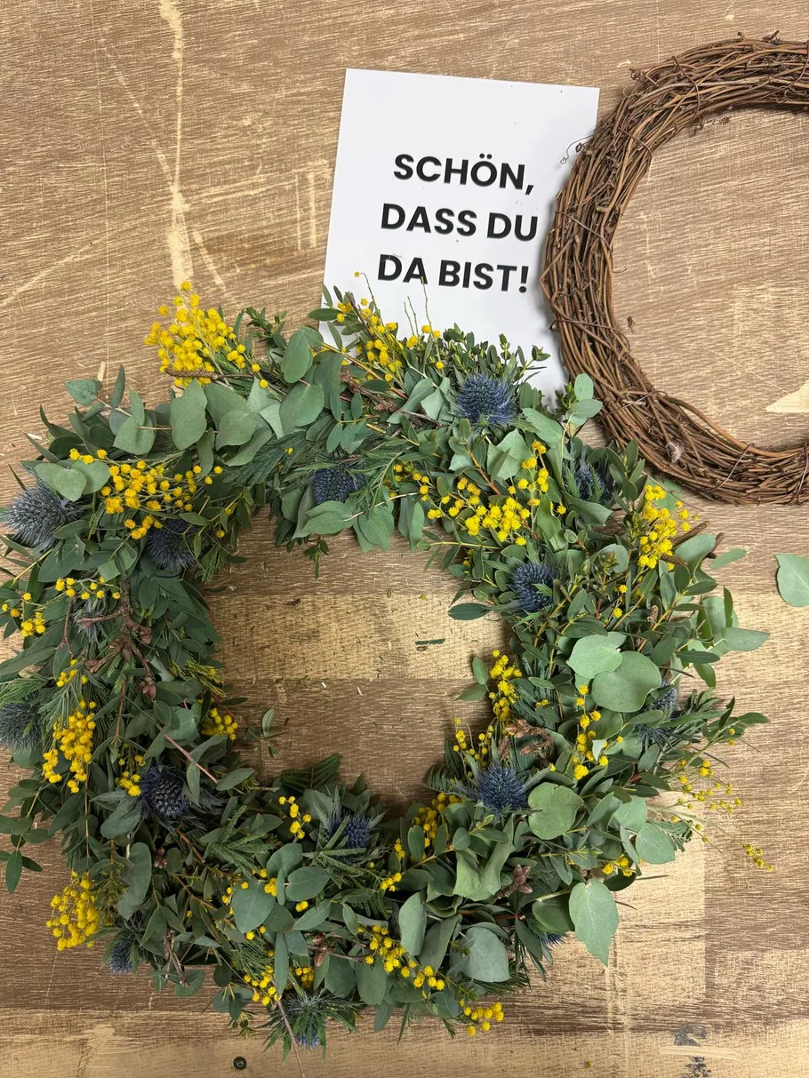 Blumenkranz mit Nachricht auf Holztisch.