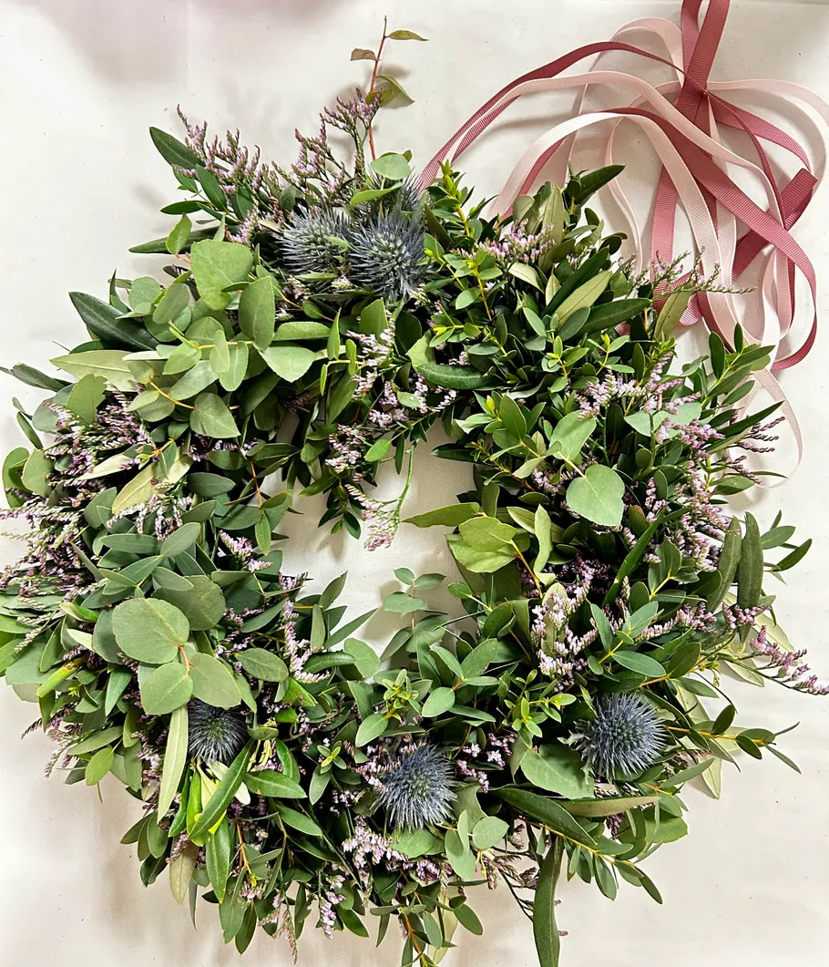 Green wreath with flowers and colorful ribbons.