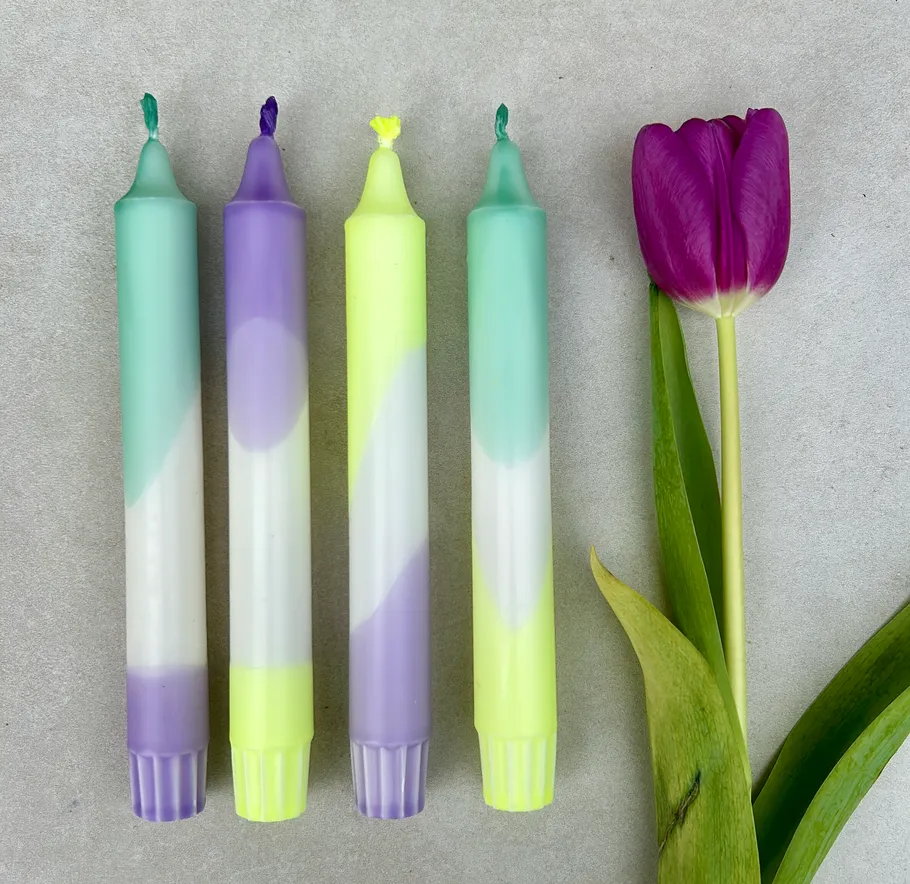 Four colorful candles beside a purple tulip.