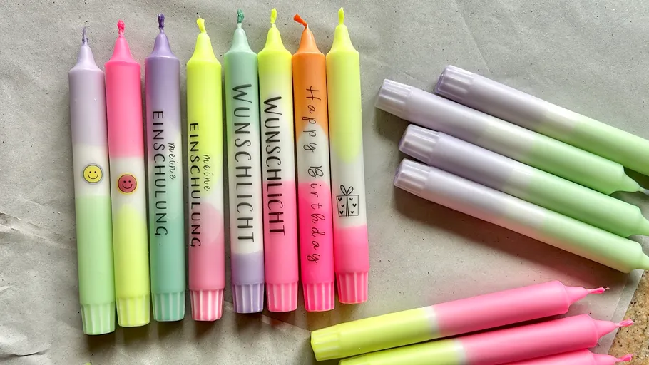 Bunte Kerzen mit Text auf Papierhintergrund.